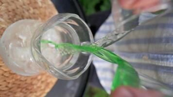 Refreshing drink is poured on summer veranda. Clip. Vertical shooting of illuminating streams of drinks in glass glasses. Pouring fresh drink with splashes in summer video