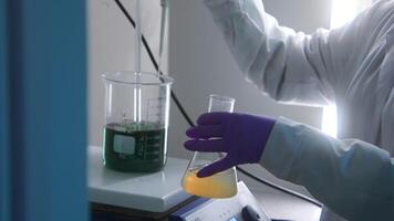 Close-up of working with chemicals in laboratory. Stock footage. Mixing of biochemical liquids for laboratory tests. Chemist mixes substances in flasks in laboratory video