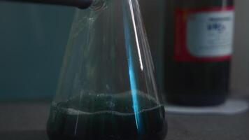 Close-up of chemical liquid is poured into flask. Stock footage. Flow of liquid filling laboratory flask. Chemical is poured into transparent flask for laboratory experiment video