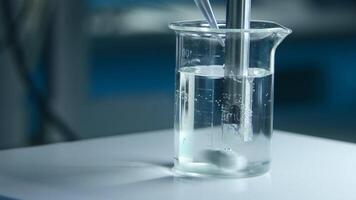 Rotating substance in glass of liquid in laboratory. Stock footage. Chemical experiment with substance and liquid in flask. Professional chemical experiment in laboratory video