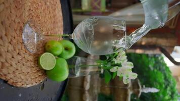 Refreshing drink is poured on summer veranda. Clip. Vertical shooting of illuminating streams of drinks in glass glasses. Pouring fresh drink with splashes in summer video