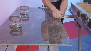 Carpenter cuts tile board. Creative. Man breaks off even part of sliced tile. Cutting tile board in modern carpentry studio video