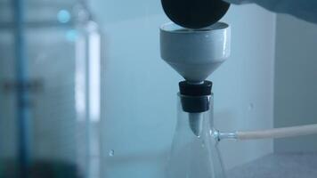 Chemist pours liquid into flask. Stock footage. Chemist conducts experiment with flask and liquid substance. Laboratory experiment with liquid and glass flasks video