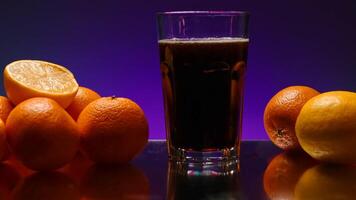 Pour pomegranate juice into a glass on a purple wall background. Stock clip. Concept of healthy diet and vitamins, oranges on a bar counter. video