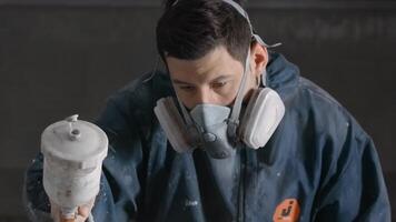 The employee carries out the repair. Creative. A man in work clothes and a puncher making a coating with gray paint through a bulletproof device. video