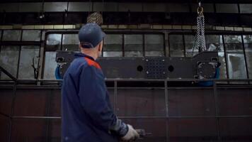 Worker controls remote control at factory. Clip. Worker moves large production parts using remote control. Remote control for moving loads of cables at factory video
