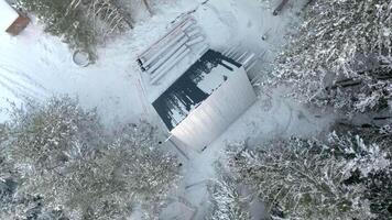 Top view of construction site of house in forest in winter. Clip. House under construction in dense coniferous forest in winter. Construction of single house in wilderness in winter video