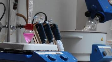 Equipment in chemical laboratory with rotating flasks. Stock footage. Rotating equipment and colored liquid in flask in laboratory. Chemical laboratory analyses with equipment video