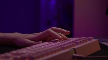 Close-up of fingers pressing on keyboard during game. Stock footage. Pink glowing keyboard for computer games. Fingers press game keys of computer keyboard video