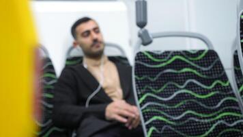 Man in public transport listening to music with white headphones. Media. Man sitting in empty bus or subway train. video