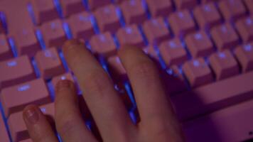 Close-up of fingers pressing on keyboard during game. Stock footage. Pink glowing keyboard for computer games. Fingers press game keys of computer keyboard video