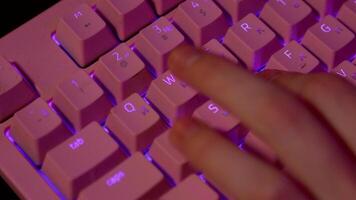 Close-up of fingers pressing on keyboard during game. Stock footage. Pink glowing keyboard for computer games. Fingers press game keys of computer keyboard video