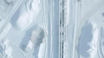 topp se av järnväg med snö. klämma. tömma snötäckt järnväg skenor i vinter. snö faller på solig dag på järnväg video