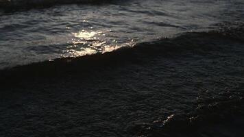 Close-up of beautiful small waves. Creative. Coastal rolling waves with solar reflection of rays. Evening tide waves with light breeze video