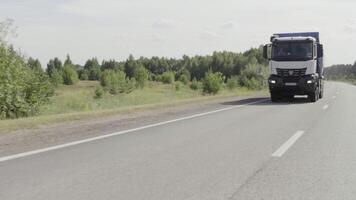 Tallinn-Estonia, 05.01.2023. Big trucks moving on a summer road. Scene. Cargo transportation in summer landscapes near a green forest and big mountains. video