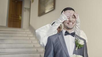 A couple of the bride and groom flirting with each other. Action. Smiling newlyweds filming in a building with bright lighting and decorations. video