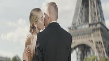 Happy couple having a good time in Paris at the Eiffel Tower. Action. Happy loving man and woman kissing near famous french tower. video