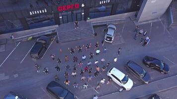 Helicopter view of the summer city. Clip. A flash mob of a group of people dancing in good weather in front of a shopping center. video