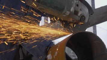 Carpenter cutting pipe with saw with sparks. Clip. Close-up of stream of sparks from circular saw. Carpenter in uniform cuts pipe with saw with sparks video
