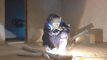 Blacksmith welder in protective mask works with metal steel and iron using a welding machine. Clip. Bright sparks and flashes in slow motion. video