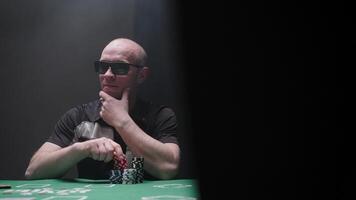 Bandit is playing poker. Action. Man is playing with poker chips. Poker player in underground club. Gambling video