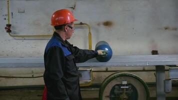 Work at the factory. Clip. A man in a helmet and a suit is working indoors with balloons. video