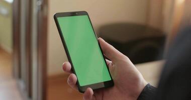 A smartphone with a green screen. Stock. A black new phone on which there is a lock and a green bright screen is shown. video