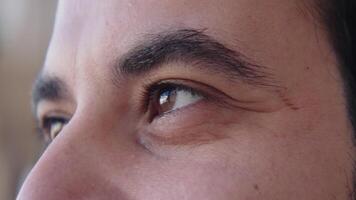 Close-up of brown eyes of man looking into distance. Action. Man with bright brown eyes looks with admiration. Joyful and admiring look of man video