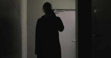 Talking on the phone. Stock. A handsome man in a black raincoat is talking on the phone with a serious face. video