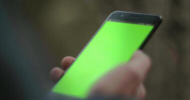 A smartphone with a green screen. Stock. A black new phone on which there is a lock and a green bright screen is shown. video