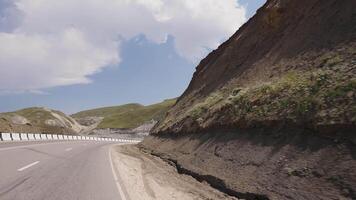 An empty road in the mountains. View from the car to the road in a quiet place with green trees around and mountains. video