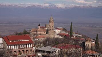 Landscape of ancient city with stone tower on background of mountains. Ancient city on hill on background of mountain range with snow. Ancient city with mountains on horizon video