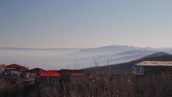 Calm landscape with mountains. Small houses against the background of high mountains and against the background of a bright cloudless sky. video