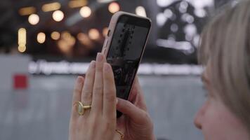 A person is capturing a special moment using their smartphone at a lively public event. Clip video