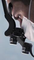 Surgeon head with professional glasses at work. Action. Close up side view of a doctor in glasses with binocular magnifiers examines something at laboratory. video