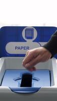 fechar acima do homem colocando uma recibo para dentro uma papel reciclando bin, reciclando falha. meios de comunicação. conceito do errado reciclado lixo, mau para a ambiente. video