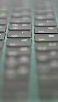 Side view of laptop or computer details, black keyboard with white symbols. Action. Extreme close up of backlit keyboard with flowing camera focus. video