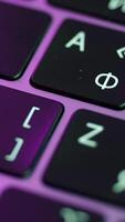 Close up of laptop or computer keyboard. Action. Concept of modern devices and technologies, buttons of a black keyboard under the purple light. video