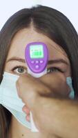 mulher dentro mascarar é verificado para temperatura dentro shopping center. meios de comunicação. visitantes para cinemas e compras centros estão verificado para temperatura usando sem contato termômetro video