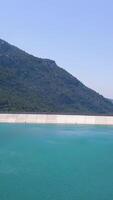 Aerial view of turquoise water in a mountain forest lake. Clip. Turkish landscape with water reservoir of azure color on the background of blue sky and forested hills. video