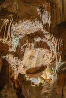 A cave with a large rock in the middle. The rock is covered in moss and has a strange shape. photo