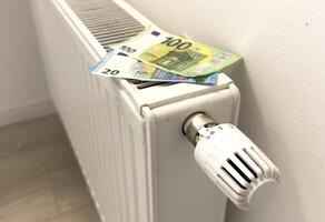 New thermostat with Euro cash on a radiator heating at home. Expensive heating costs symbolic image. photo