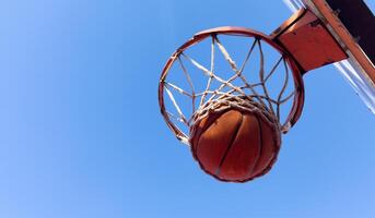 Basketball scoring a basket as it goes through the hoop and making a swish in the net photo