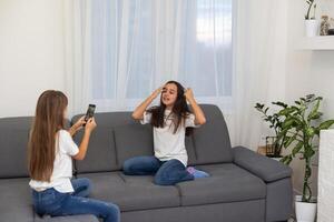 Child with smartphone at home. Two kids using smart phone, surfing internet or using social media. Two kids using online mobile phone, call, watching content, playing games, sitting on couch photo