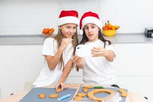 Two girls sisters are playing around in the kitchen after making Christmas cookies, they draw with flour on the table and on their faces. Christmas, New Year concept photo