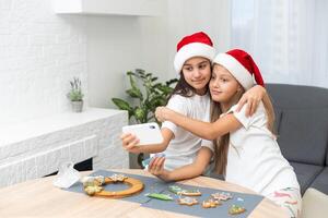 Two girls sisters are playing around in the kitchen after making Christmas cookies, they draw with flour on the table and on their faces. Christmas, New Year concept photo