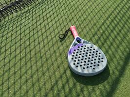 Paddle tennis racket, ball and net on the grass photo