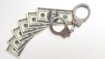 Dollars of hundred and fifty dollars lie on a floor and from above handcuffs for detention of the corrupt official on polichny are put. photo