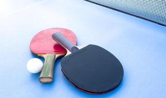 wooden rackets for playing table tennis and a net on a blue background, top view photo