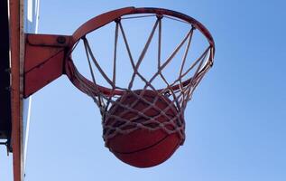 Bottom view of red basketball hoop with ball flying in. Copy space photo